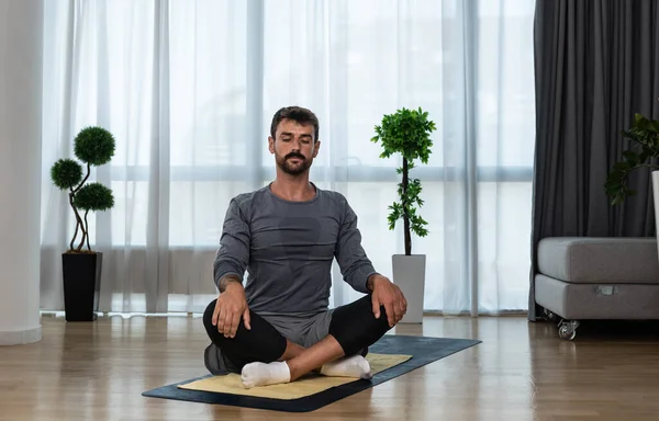 Young man cancer survivor practicing home workout yoga training, stretching muscles and breathing exercise for healthy life after long struggle with sickness and pain.