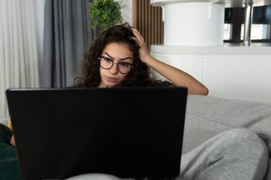 Tatmin olmuş bir kadın rahat koltukta dinleniyor, evinde dizüstü bilgisayar kullanıyor, sosyal ağda arkadaşlarıyla sohbet eden mutlu bir kız, tembel bir hafta sonu geçiriyor, film izliyor, internetten alışveriş yapıyor, e-posta yazıyor.