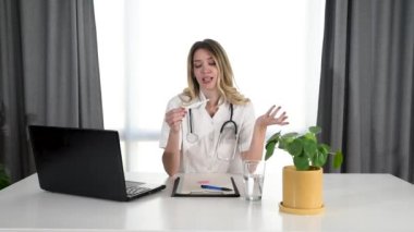 Genç bayan doktor online sunum ve doktor muayenehanesinden hamilelik testi hakkında konuşma. Tıp uzmanı kameraya hamileliğin önlenmesi ve cinsel eğitim hakkında konuşuyor..