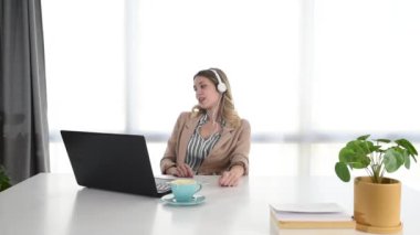 Ofiste dizüstü bilgisayarla çalışan genç bir iş kadını kulaklıkla müzik dinliyor. Kadın iş adamı rahatlatıcı bir melodiyle iş zamanının tadını çıkarıyor..