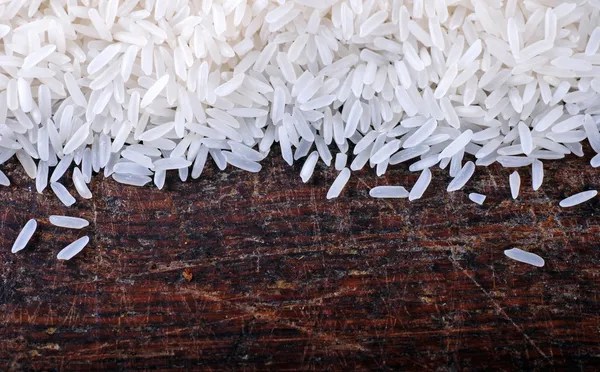 Granica długo białe ziarna ryżu na tle drewna — Zdjęcie stockowe