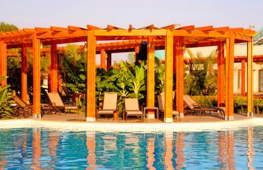 Resort havuz, ahşap pergola ve şezlonglar