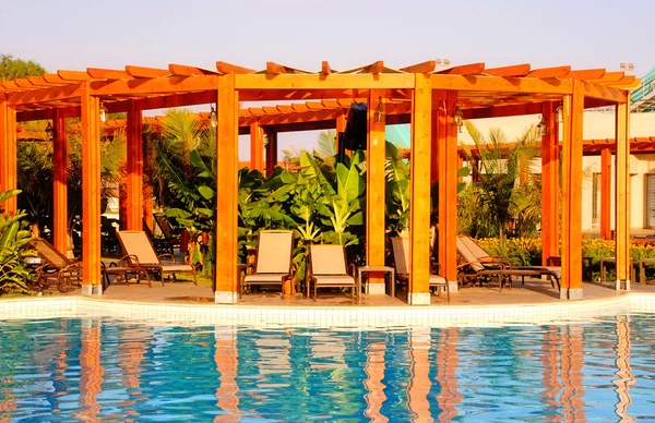 Resort havuz, ahşap pergola ve şezlonglar