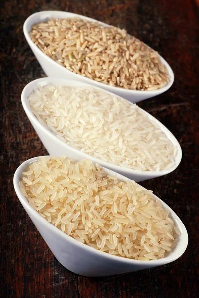 Brown rice, wild rice and white (jasmine) rice on wood board — Stock Photo, Image