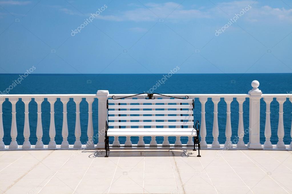 White bench, balustrade and empty terrace overlooking the sea