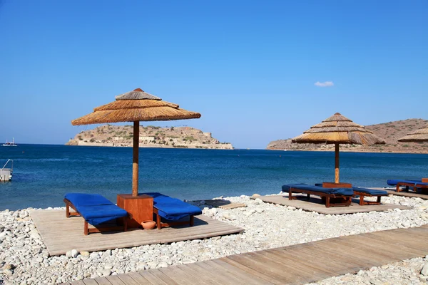 Sun beds and umbrellas on the beach of Mediterranean sea (Crete, — Stock Photo, Image