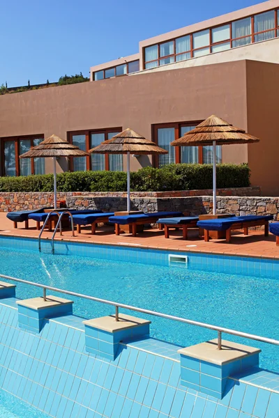 Junto a la piscina con cama de piscina y sombrilla en un resort de lujo —  Fotos de Stock