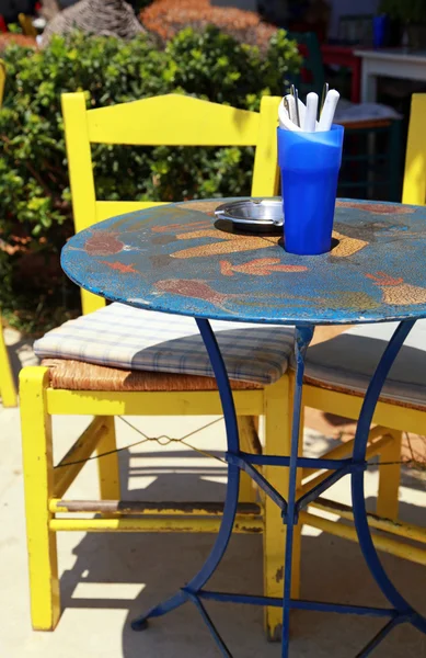 Buiten restaurant met blauwe tafel en gele stoel (Griekenland) — Stockfoto