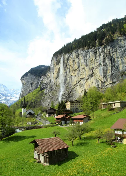 Bergdorf mit Kirche und Wasserfall, Alpen, Schweiz . — Stockfoto