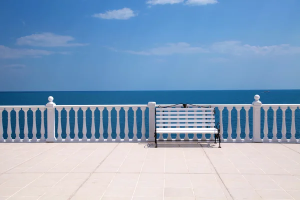 Banc blanc, balustrade et terrasse vide donnant sur la mer — Photo