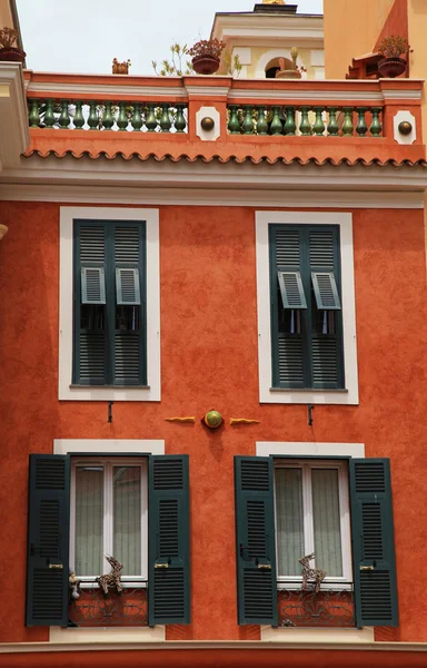 Red stucco house with old green shutter windows in Monaco