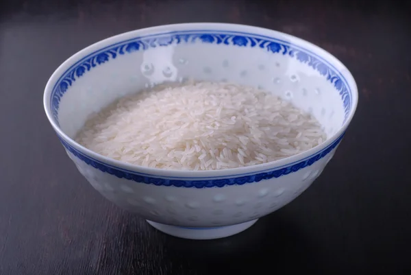 Cuenco de arroz blanco sin cocer sobre fondo de madera . —  Fotos de Stock