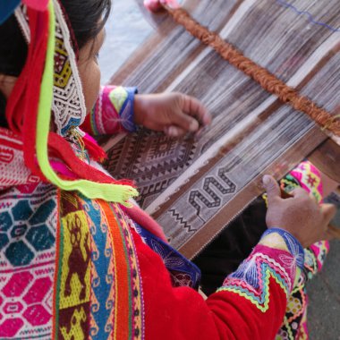 Cusco, Peru - 1 Temmuz 2022: Bir Keçuva kadını alpaka yünü kullanarak geleneksel Andean tekstili dokuyor