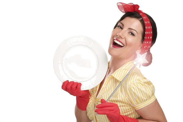 Молодая красивая женщина домохозяйка показывает волшебную палочку на тарелках — стоковое фото