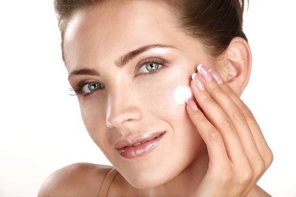 Hermosa modelo aplicando tratamientos de crema cosmética en su cara — Foto de Stock