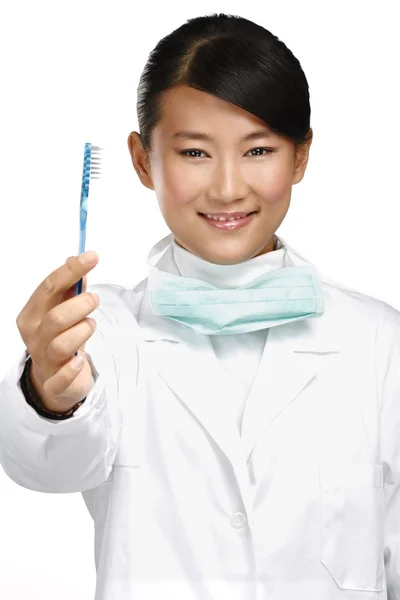 Souriant jeune asiatique femme dentiste montrant une brosse à dents — Photo