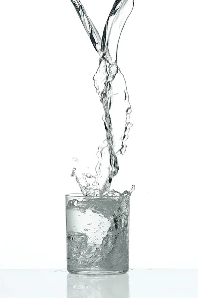 Flujo de agua fresca salpicando en un vaso transparente — Foto de Stock