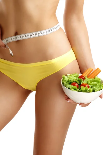 Gros plan d'une femme mesurant ses hanches avec une salade à la main — Photo