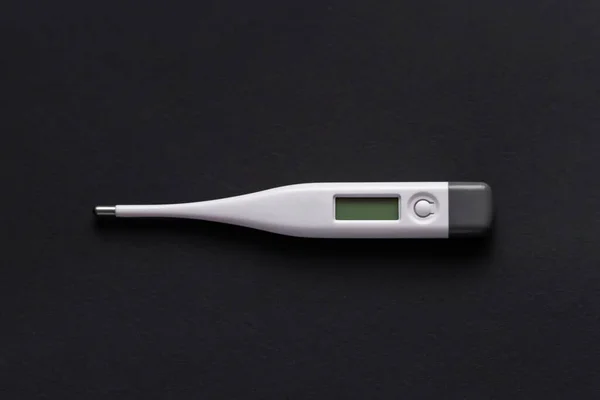 white electronic thermometer on a black background