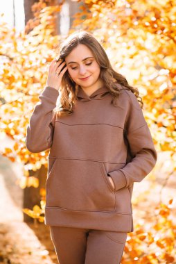 Young woman spends time in an autumn park. Sunny weather. Fall season.