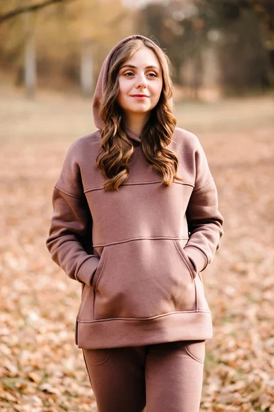 Young woman in hoodie in an autumn park. Sunny weather. Fall season.