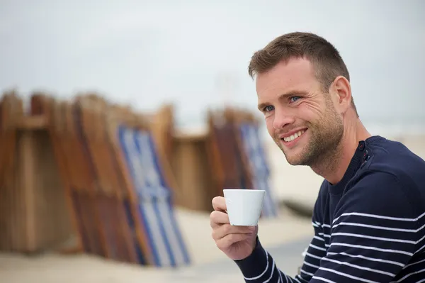 Giovane uomo che beve il suo caffè in spiaggia — Foto Stock