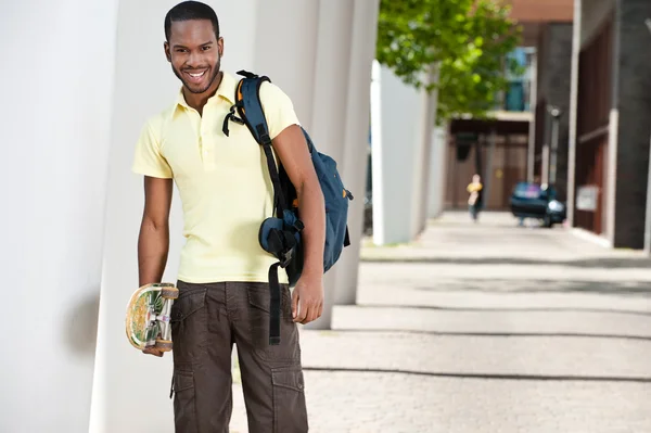 Porträtt av en balck student med skateboard och väska — Stockfoto