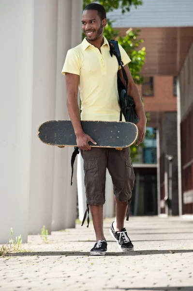 Young man with a skateboard and bag over his shoulder — Stock Photo, Image