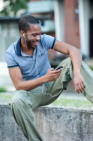 Young african guy listening to music on headphones — Stock Photo, Image