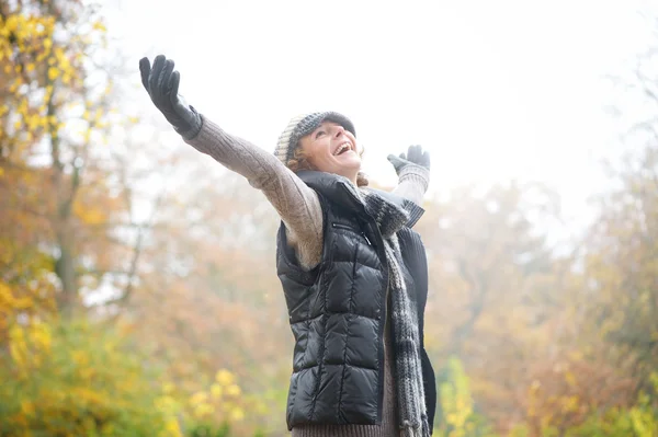 Zorgeloos vrouw met outstreched armen in de herfst — Stockfoto