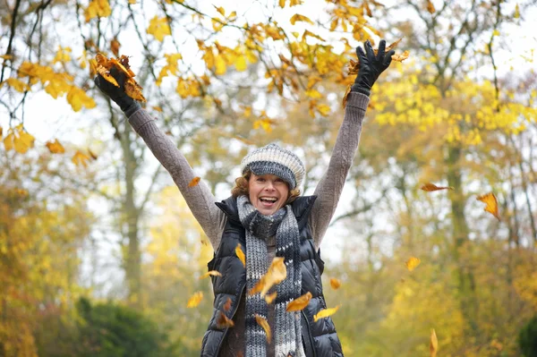 Mooie midden leeftijd vrouw gooien gele bladeren — Stockfoto