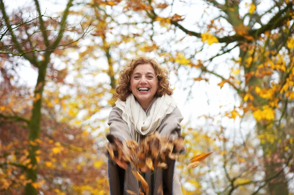 Mujer feliz lanzando hojas — Foto de Stock