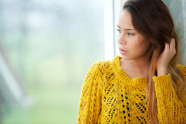 Mooie vrouw kijkt uit raam — Stockfoto