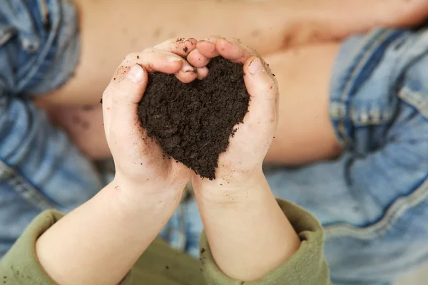 Руки ребенка держат почву в форме сердца — стоковое фото