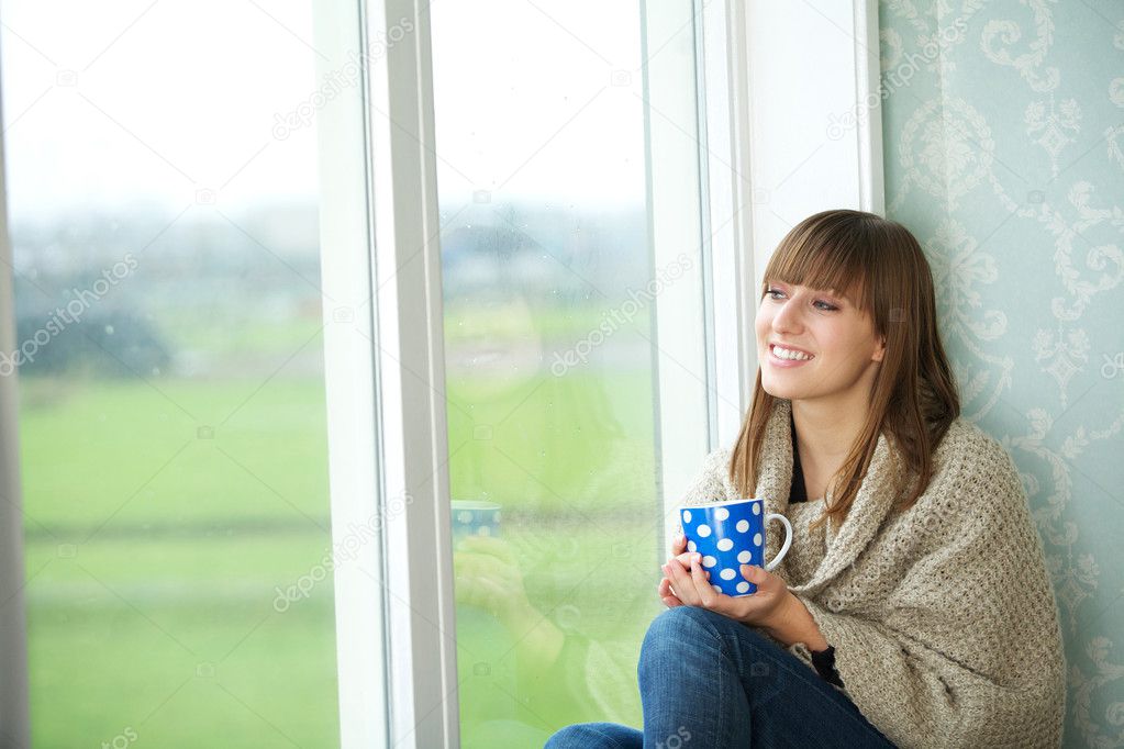 Young Woman Sitting by Window with Cup of Tea
