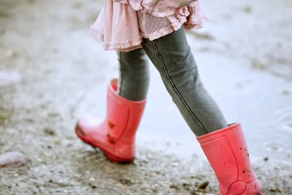 Девочка ходит на улице в красных сапогах Стоковая Картинка