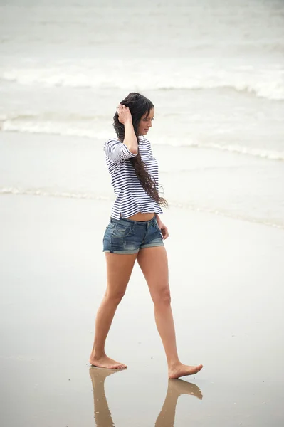 Porträtt av en ung kvinna som promenerar på stranden ensam — Stockfoto