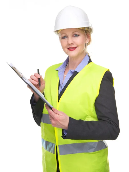 Portrait of a businesswoman in safety vest and hard hat writing on clipboard — Stock Photo, Image