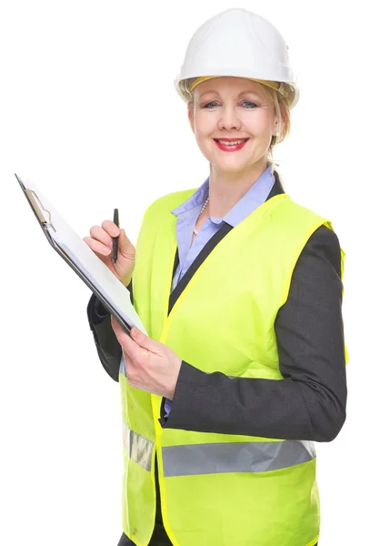 Portrait of a smiling woman in safety vest and hardhat writing on clipboard — Stock Photo, Image