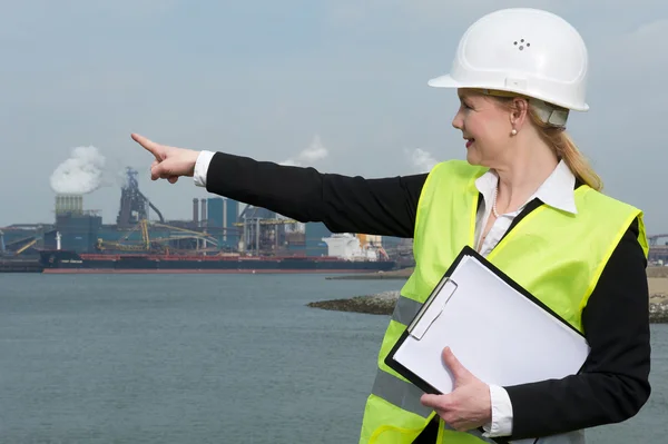 Inspektur wanita di hardhat dan rompi pengaman menunjuk pada situs industri — Stok Foto