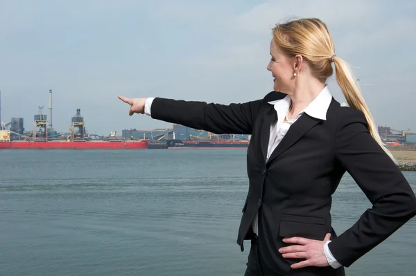 Empresaria sonriendo al aire libre y señalando con el dedo a los barcos en el puerto —  Fotos de Stock