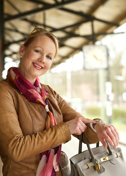 Retrato de una hermosa mujer sonriendo y señalando su reloj — Foto de Stock