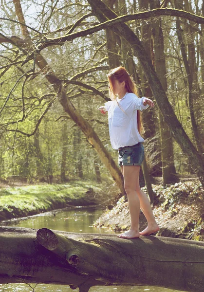 Portrait of a young woman walking over tree trunk — Stock Photo, Image