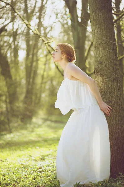 Beautiful young bride in white wedding dress standing outdoors — Stock Photo, Image