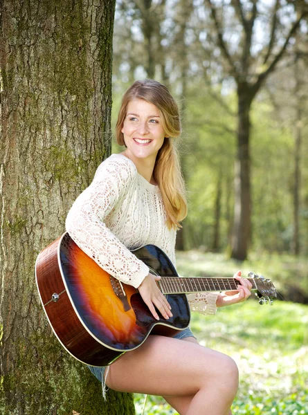 Portrait of a young woman smiling with guitar outdoors — Stock Photo, Image