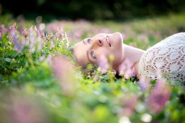 Beautiful young woman lying in meadow of flowers — Stock Photo, Image