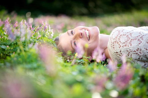 快乐的年轻女人，躺在草地上的花朵 — 图库照片