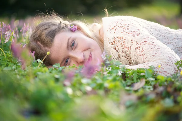 Jovem feliz deitado na grama e flores — Fotografia de Stock