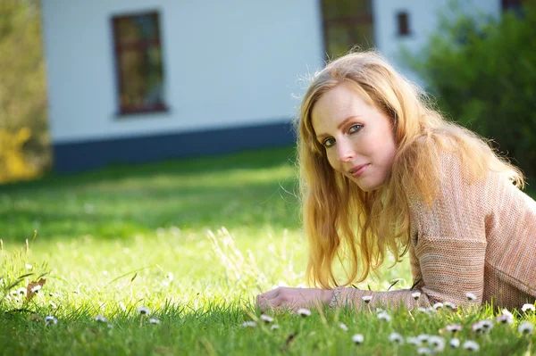 Jonge vrouw ontspannen op gras buitenshuis — Stockfoto