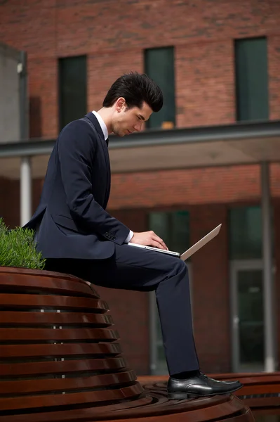 Jonge zakenman die op laptop buiten het kantoor werkt — Stockfoto